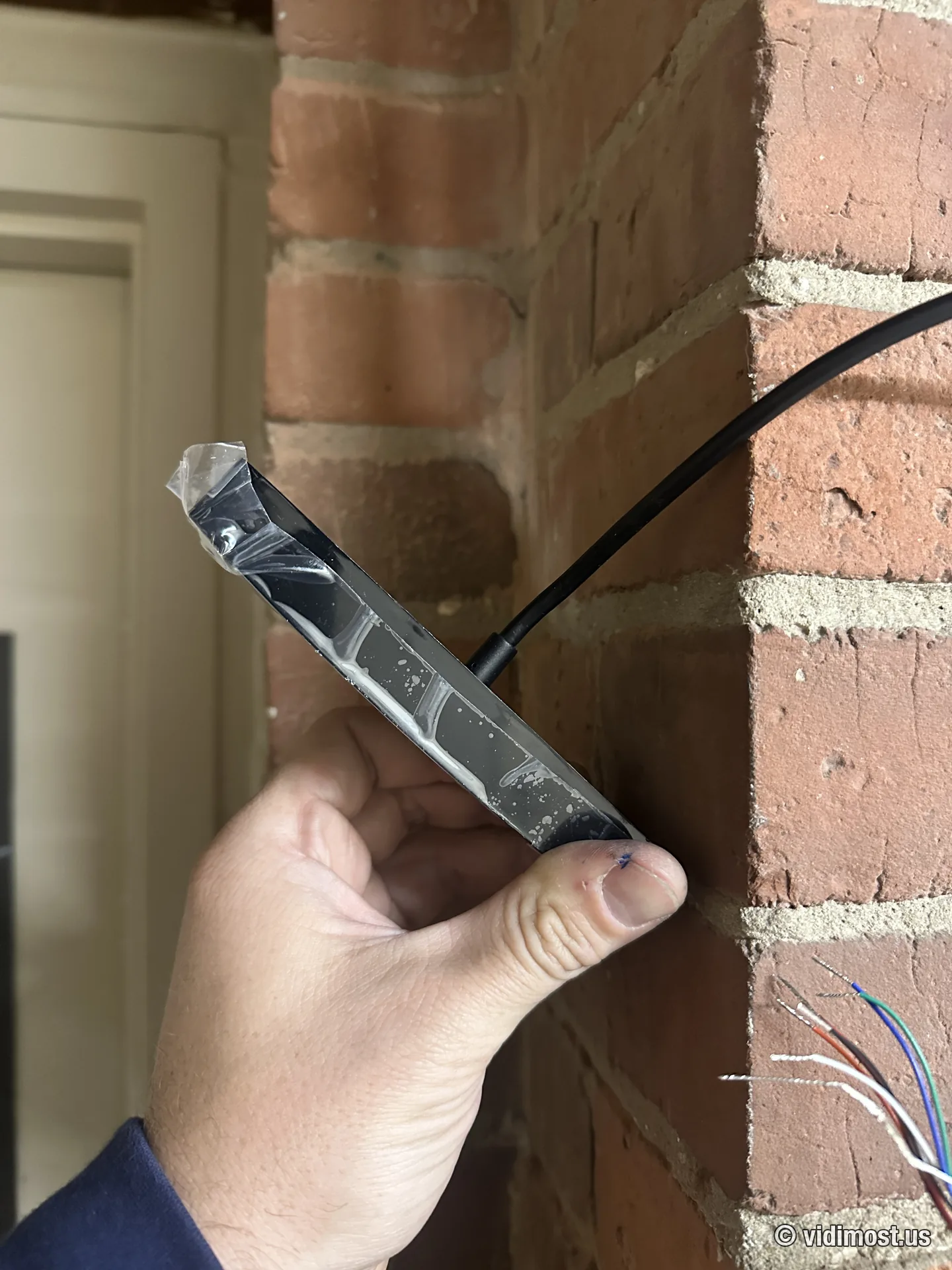 Technician holding a Brivo mullion reader during installation at a brick entrance