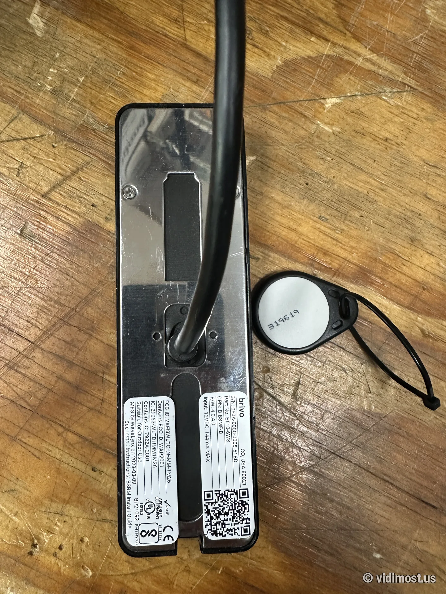 Back label of a Brivo B-BSMF-B reader next to a Brivo key fob on a workbench