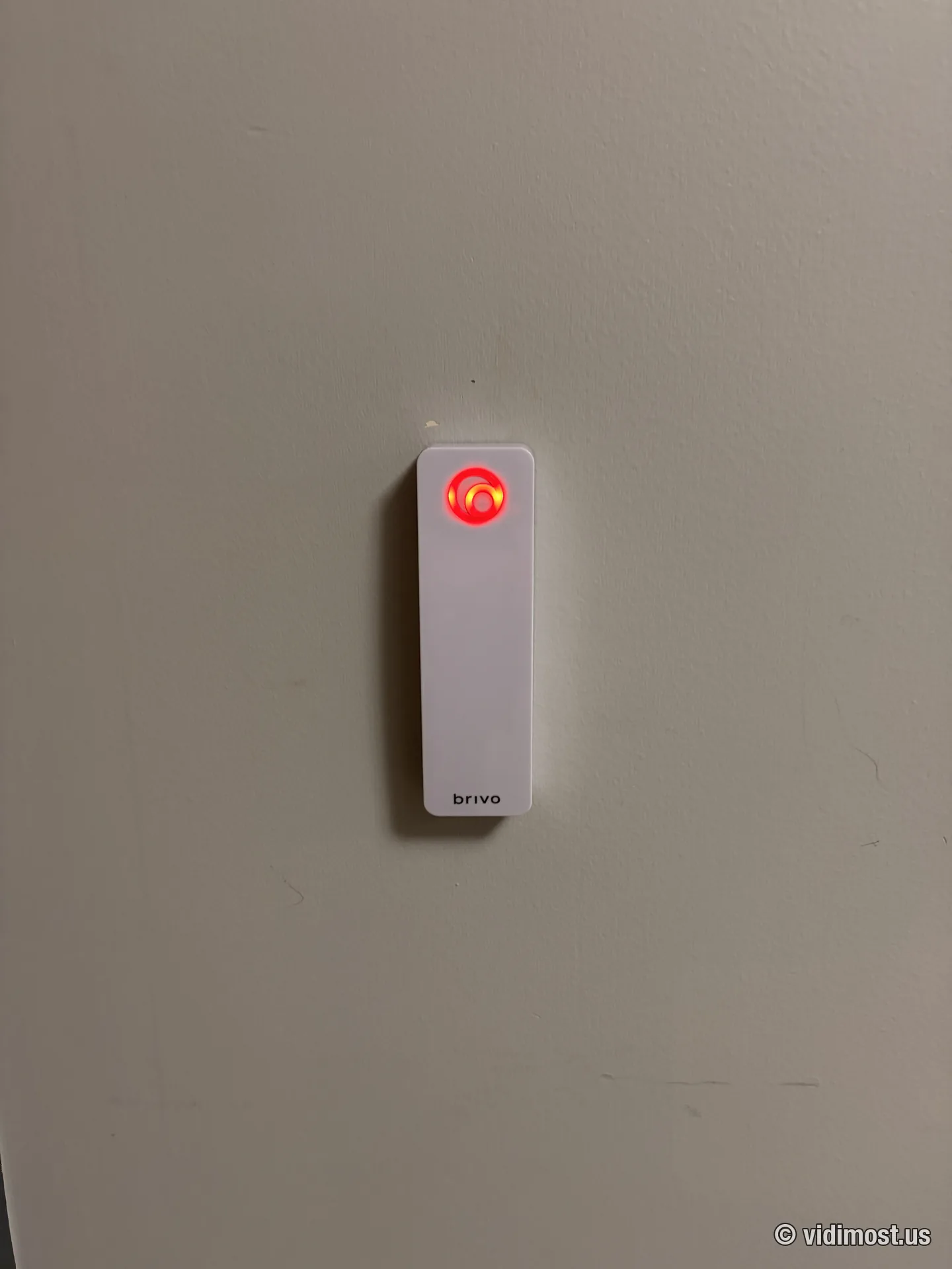 White Brivo smart reader with red LED ring on a painted interior wall