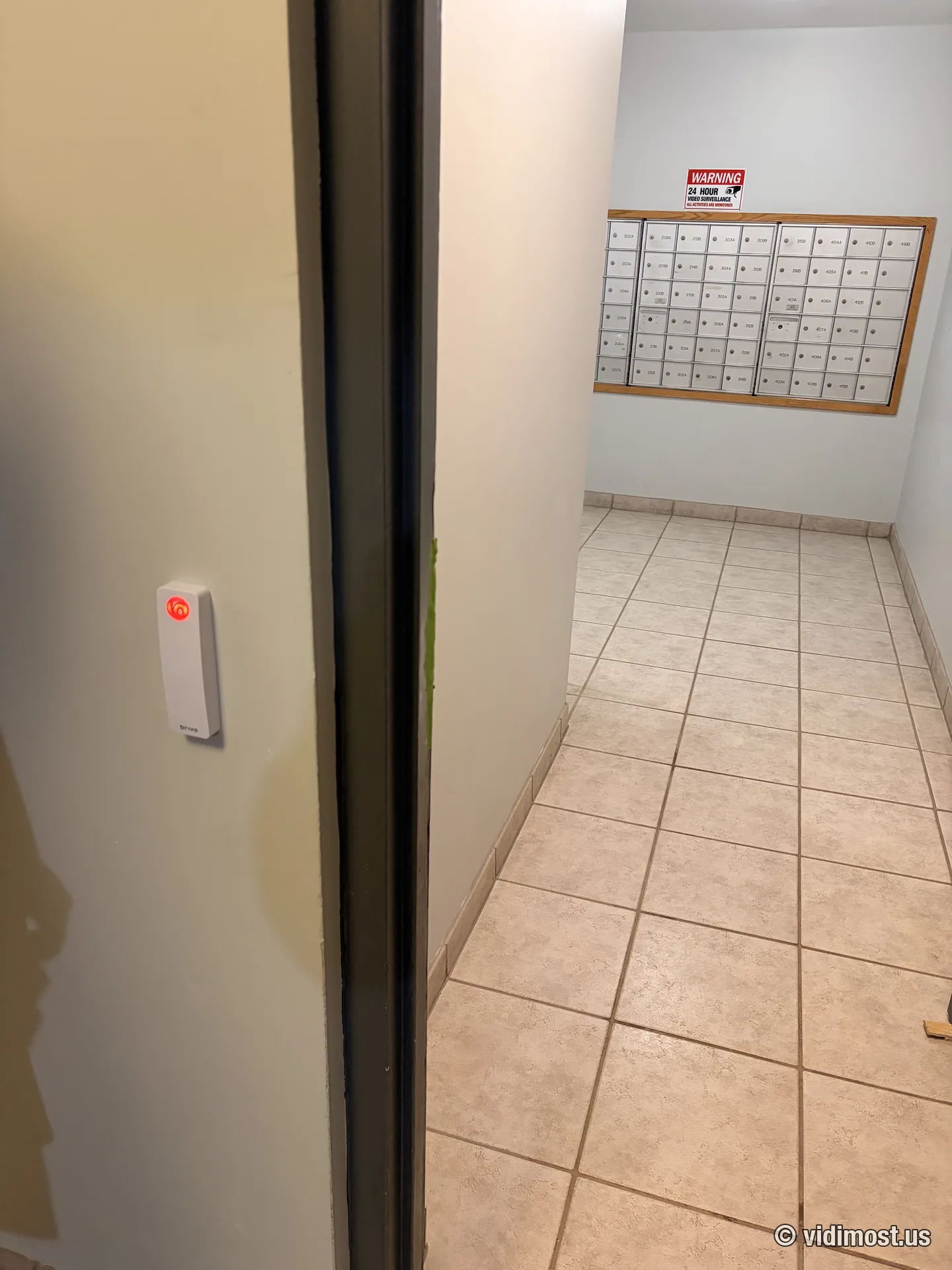 White Brivo mullion reader at an apartment building mailroom entrance with tenant mailboxes visible